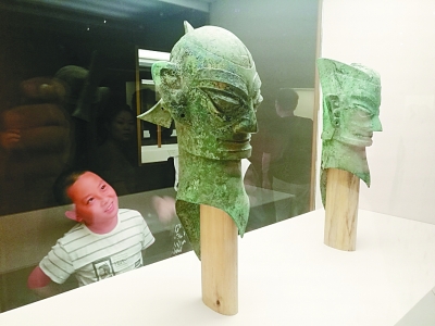 一位小观众对国家博物馆“古蜀华章展”中的青铜头像产生了兴趣。李韵 摄