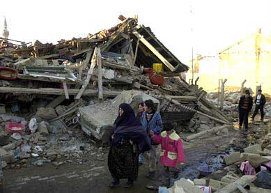 土耳其大地震--人们怅然地走过自家坍塌的房屋