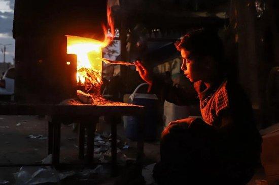 ▲11月11日，一名男孩在加沙地带南部城市汗尤尼斯街头用柴火做饭。新华社发（里泽克·阿卜杜勒贾瓦德摄）