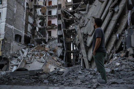 10月8日，一名巴勒斯坦人在加沙城查看以色列空袭后的建筑废墟 / 图源：新华社