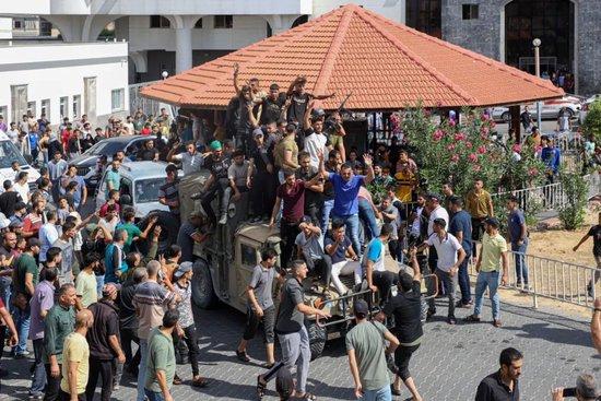 10月7日，在加沙城，巴勒斯坦人登上一辆以色列军用车辆 / 图源：视觉中国