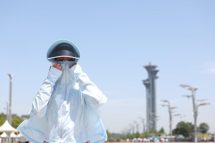 ▲2023年7月6日，北京奥林匹克公园景观大道，小朋友整理自己的防晒服。当日，北京发布了今年以来的第二个高温红色预警，最高气温达40℃以上。新京报记者 王飞 摄