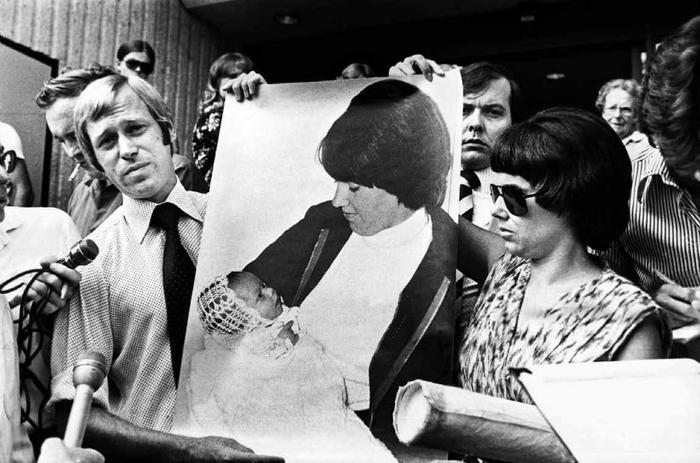 ·1981年2月20日，林迪和丈夫迈克尔在法院门前的台阶上展示自己怀抱女儿的照片。
