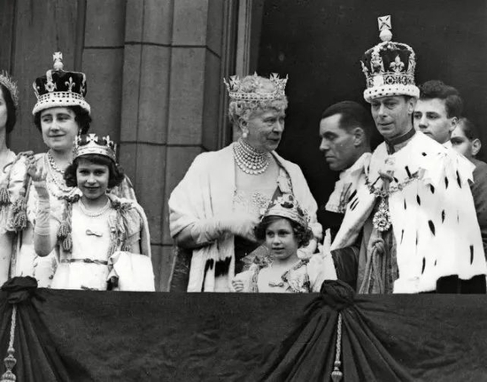 1937年5月12日，乔治六世国王一家站在白金汉宫的阳台上，王太后玛丽正在和儿子交谈，当时的伊丽莎白公主（左1）和玛格丽特公主（左4）