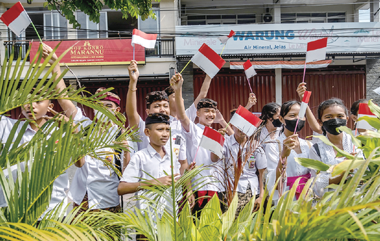 当地时间14日，印度尼西亚中学生挥舞印尼国旗欢迎前来参加G20峰会的代表。 （视觉中国）