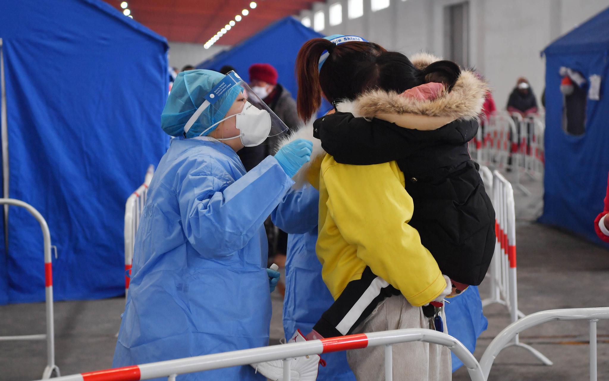 工作人员在安慰一名害怕做核酸采样的小姑娘。摄影/新京报记者 李木易