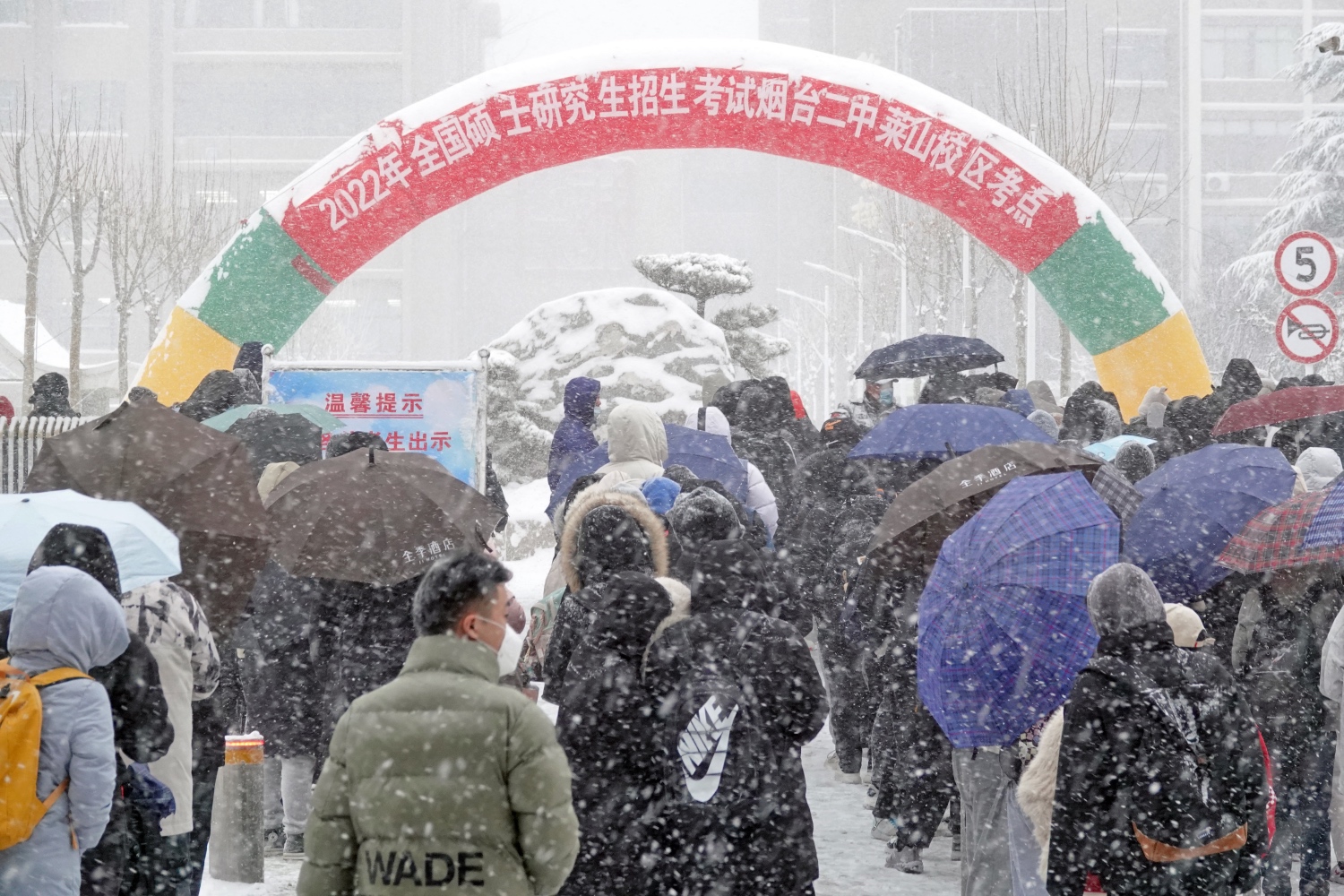  2021年12月25日，山东烟台，参加研究生考试的考生们顶风冒雪进入山东烟台二中莱山校区考点  图源：视觉中国