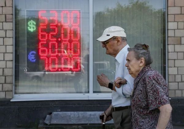 ▲6月29日，俄罗斯莫斯科的一对老年人走过一个货币兑换处，屏幕上显示美元和欧元对俄罗斯卢布的汇率。（欧洲图片新闻社）