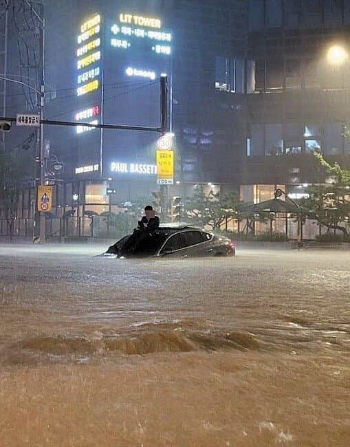 首尔遭遇特大暴雨，市民坐在车顶
