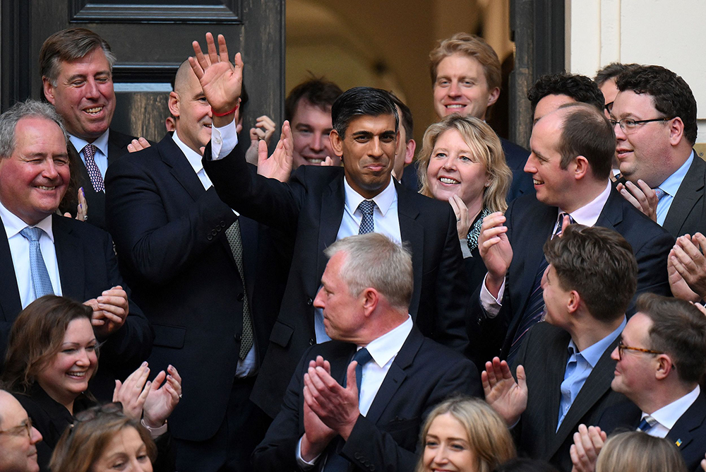 当地时间2022年10月24日，英国伦敦，英国保守党党首里希·苏纳克（中）抵达位于伦敦市中心的保守党总部时挥手致意。人民视觉  图