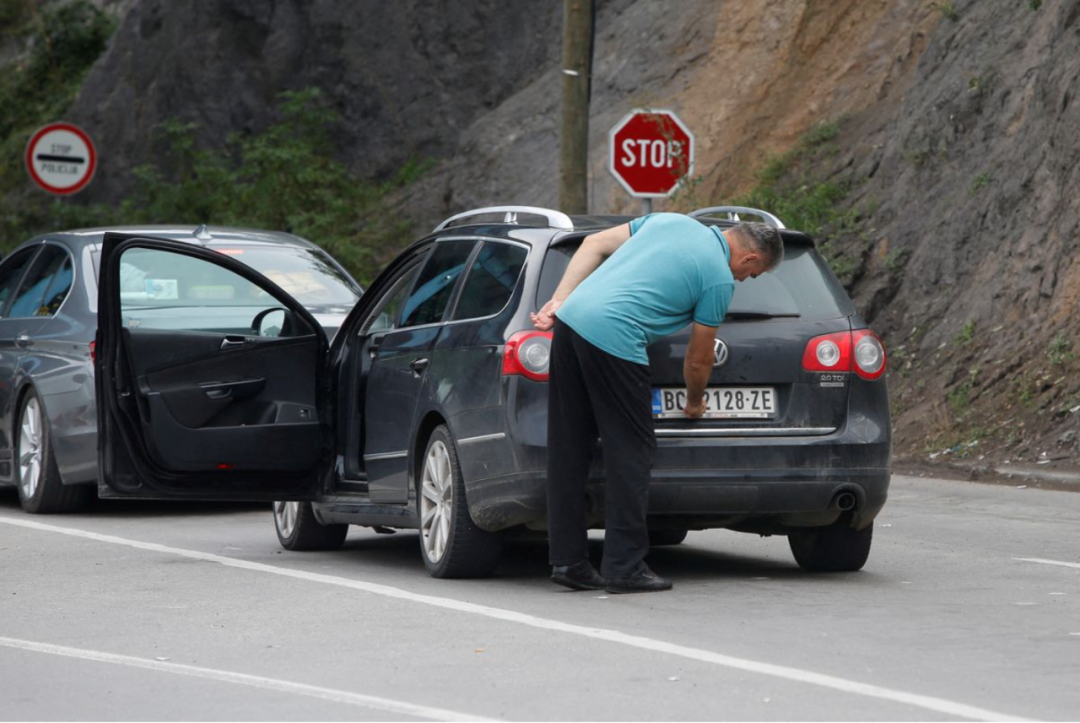 9月1日，一名司机在科索沃过境点更换车牌贴纸。图源：路透社