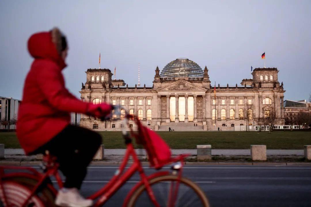 ▲德国柏林，一名女子骑车经过议会大厦。图/新华社/美联